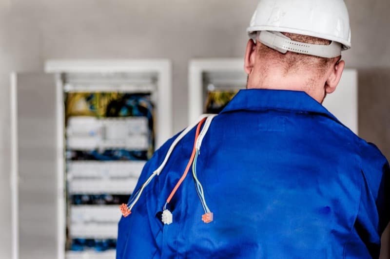 Électricien casqué devant un tableau électrique en cours de câblage